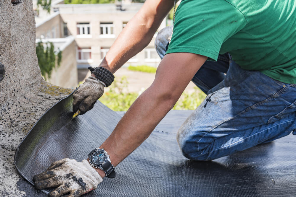 Roofer applying protective waterproof layer to roof surface, ensuring durability and leak prevention